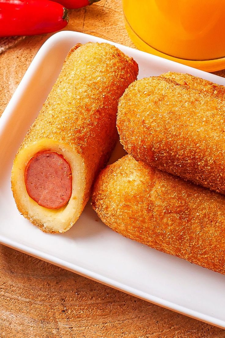 Golden enroladinhos wrapped around sausage on a white plate