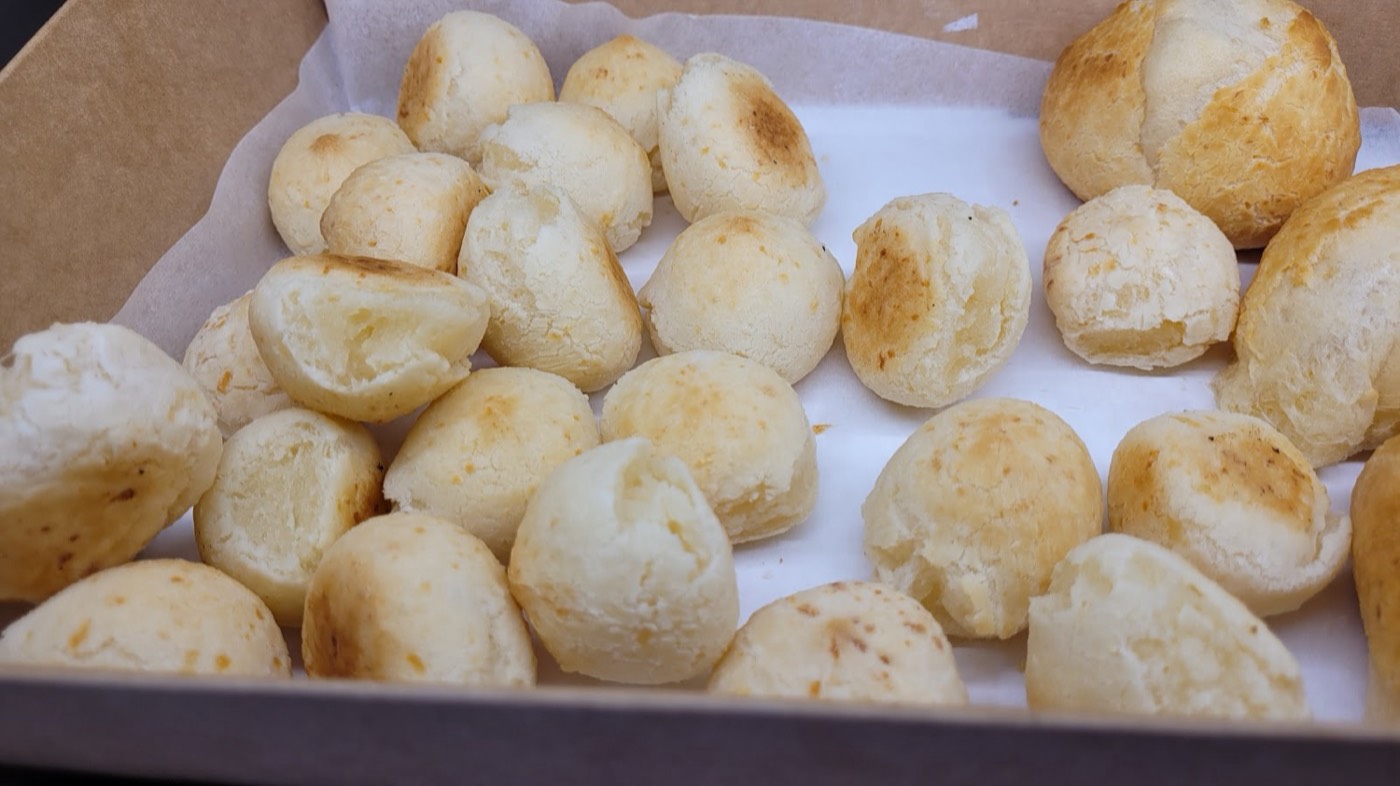 A box of freshly baked golden pão de queijo, Brazilian cheese bread