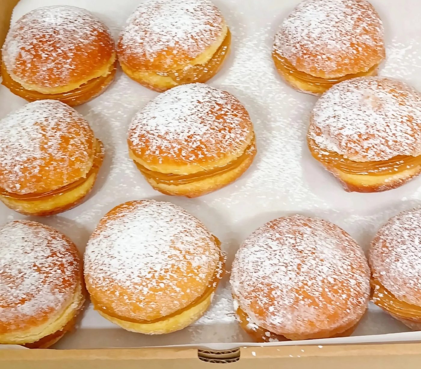A tray of sugar-dusted sonhos doughnuts filled with doce de leite