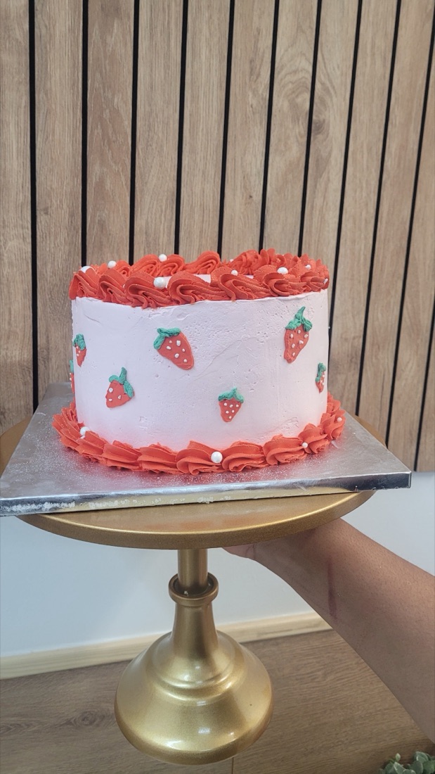 A pink strawberry-cream celebration cake with fondant strawberries
